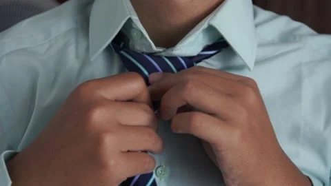 Close up of a businessman hands fixing or adjusting a striped blue necktie on hi Video stock 337761008