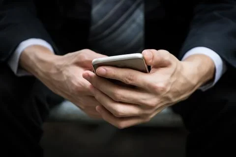 Close up of businessman hands holding smartphone in blurred background. Stock Photos