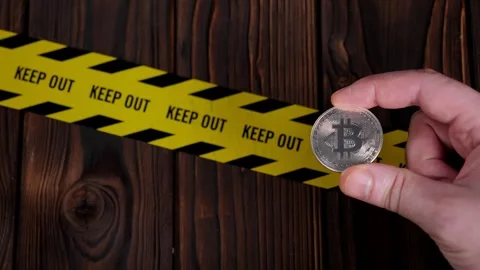 Close up of businessman holding silver bitcoin with yellow warning tape KEEP OUT Stock Footage 300833570
