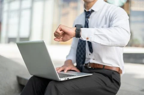 Close up of businessman office worker checking time on watch while using la.. Foto stock