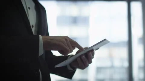 Close-up of a businessman in a suit using a tablet next to a big window Stock Footage