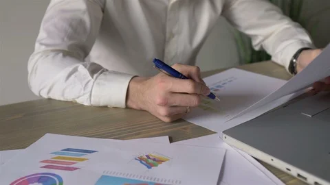 Close-up businessman takes notes in documents, graphs and works behind a laptop Stock Footage 110949005