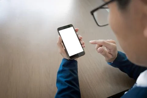 Close up of a businessman using mobile smart phone on wooden table, business Stock Photos