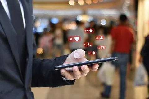 Close up of businessman using mobile smartphone with social media icons over  Stock Photos