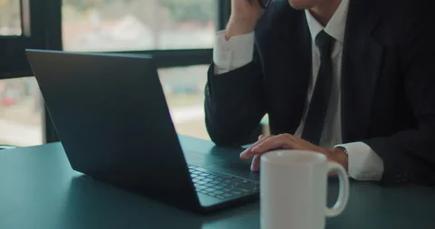 Close up of a businessman working on a laptop while holding a phone. Stock Footage 140191083