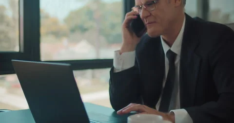 Close up of a businessman working on a laptop while talking on the phone. Stock Footage 140191331