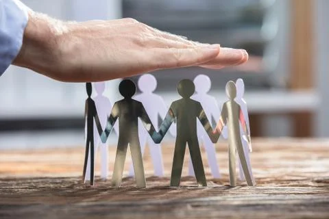Close-up Of A Businessperson Protecting Human Cut-out Figures Stock Photos