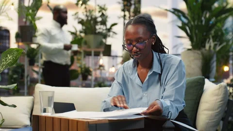 Close up of businesswoman reading project notes in rooftop lounge 動画素材 345164439