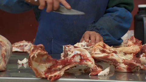 Close-up. a butcher in an apron cuts large chunks of meat with a knife. Stock Footage 95990814
