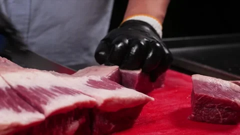 Close-up of a Butcher Skillfully Slicing Raw Beef Steak on a Red Cutting Board Stock Footage 331634897