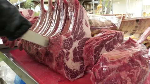 Close-up of Butcher Slicing Fresh Marbled Ribeye Beef Steak for Barbecue - 4K Hi Видео 338212933