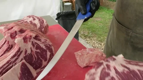 Close-up of Butcher Slicing Raw Marbled Tomahawk Ribeye Steak on Red Board Stock Footage 338212951