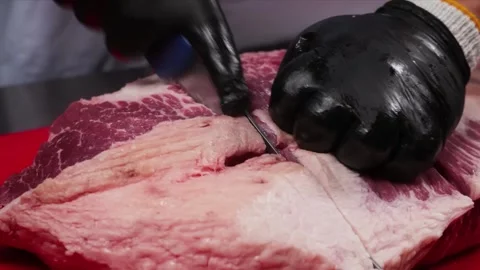 Close-up of a butcher trimming raw beef brisket fat with a sharp knife Stock Footage 331635199