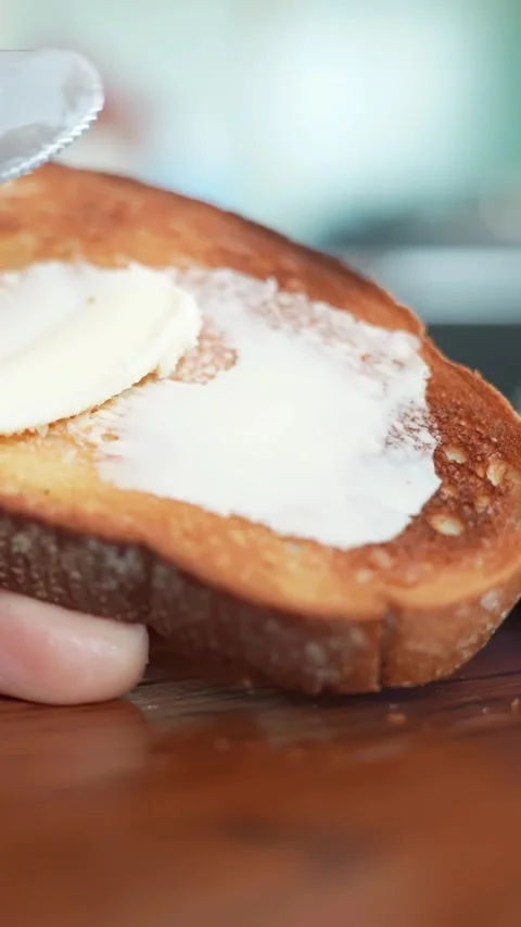 Close-up of butter being spread on toasted bread with a butter knife on a Stock Footage 332044515