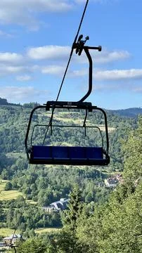 Close-up of a cable car bench with mountains, sky, and trees in the background Stock Photos