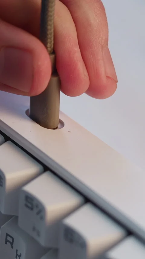 Close-up cable plug connecting into recessed port on white keyboard, showing Stock Footage 346986973