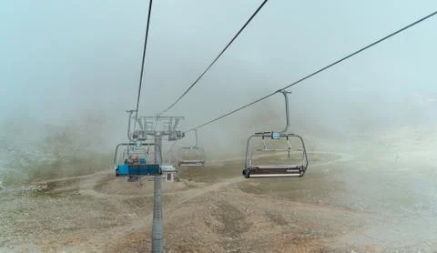 Close up of cableway in clouds. Clouds enveloping modern ropeway with benches in Foto stock