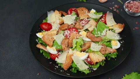 Close-up of a Caesar Salad in a black plate against a Black Background Stock Footage 237703445