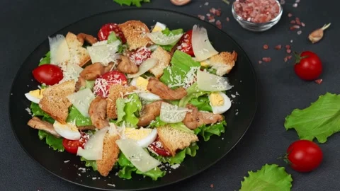 Close-up of a Caesar Salad in a black plate against a Black Background Video stock 237703455