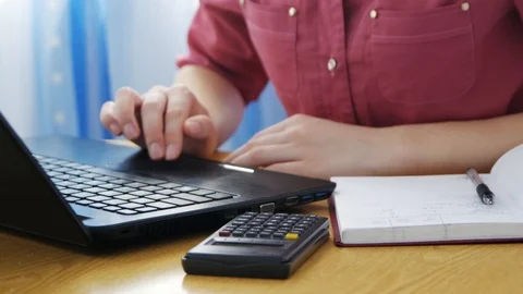 Close up calculator on table, female hands typing on laptop, student writing  Stock-Footage 107184466