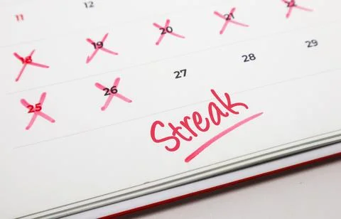 Close up of a calendar page with red marks on dates and the word Streak, sy.. Stock Photos