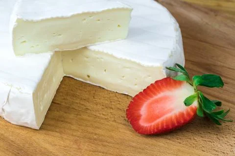 Close up of Camembert cheese brie with triangle cut out and fresh sliced stra Stock Photos