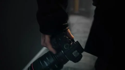 Close-up of a camera in the hand of a man walking down a corridor. The camera is Stock Footage 252273889