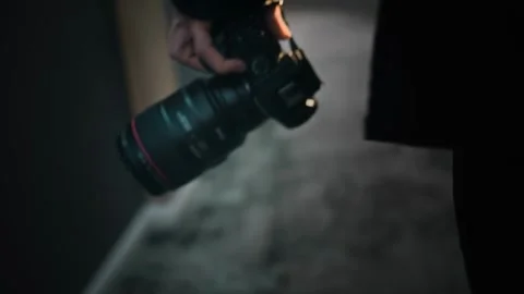 Close-up of a camera in the hand of a man walking down a corridor. The camera is Stock Footage 252274361