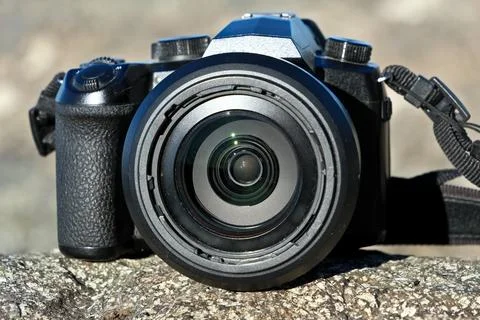 Close-Up Camera Lens on Rocky Surface. Mirrorless Camera Perched on Huge Rock. Stock Photos