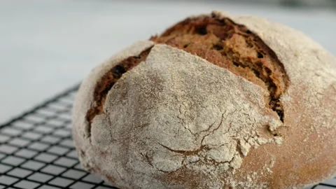 Close up camera movement. Beautiful rustic rye bread lies on the wire rack Stock Footage 148573600