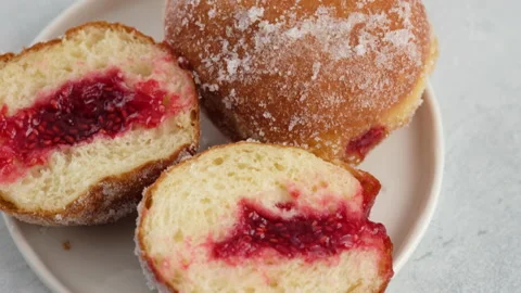 Close-up camera movement. Berliners. Donuts with raspberry jam lie on a plate on Stock Footage 146868504