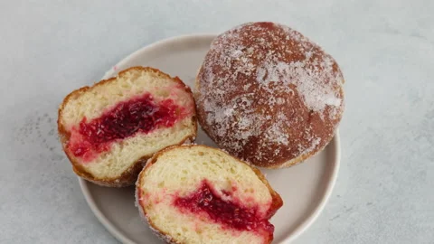 Close-up camera movement. Berliners. Donuts with raspberry jam lie on a plate on Stock Footage 152485146