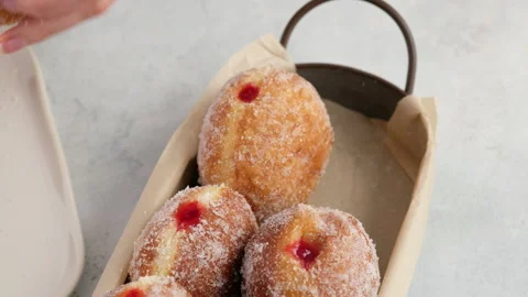 Close-up camera movement. Berliners. Female hands put donuts with raspberry jam Video stock 146867663