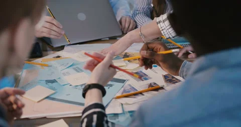Close-up camera moves around multiethnic team working together behind table on Stock Footage 106155923