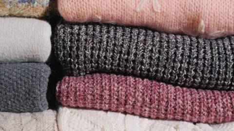 Close up camera panning across stacks of neatly folded warm knit sweaters i.. Видео 335060152
