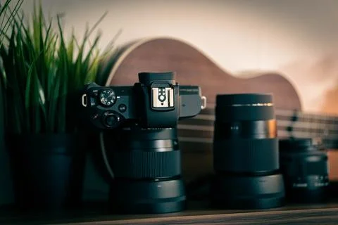 Close-up of a camera setup with multiple lenses, a guitar in the background, and Stock-Fotos