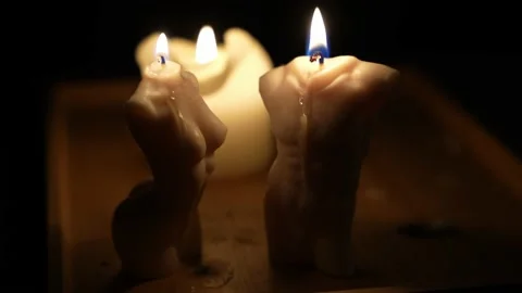 Close up camera shot of burning candles. Candles in silhouettes of woman and man Stock Footage 238975309