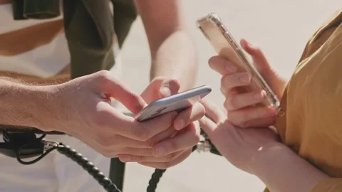 Close camera view of two people holding smartphones while standing near scooter Stock Footage 307498285