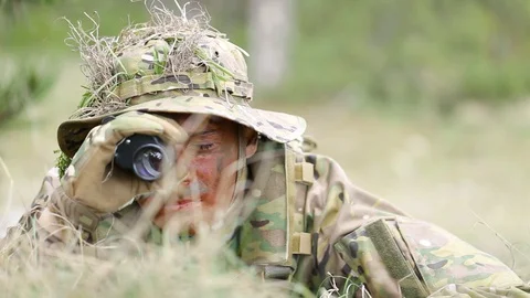 Close-up. Camouflage face paint man watching through field glasses. Ghillie suit Stock Footage 127632140