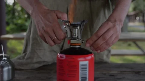 Close-up of camper lighting compact gas stove on orange fuel... Stock Footage 322811596