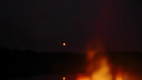 Close-up of campfire against the moon reflected in the lake in the evening. Stock-Footage 283082245