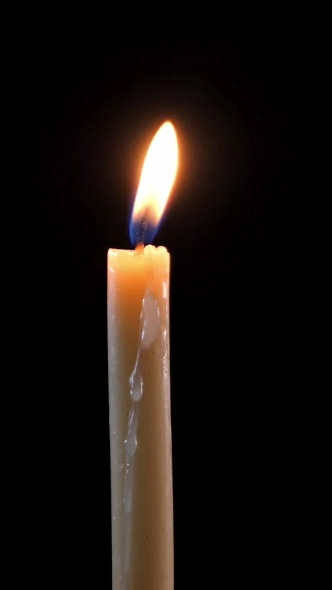 Close-up of a candle on a black background. Long burning candle. Stock Footage 309615976