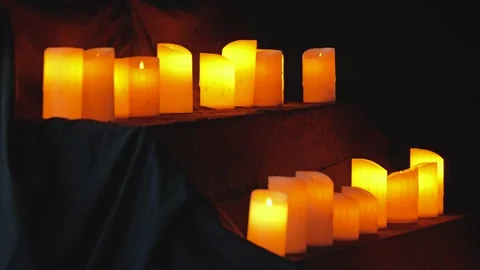 A close-up of candles arranged beautifully, casting a glow in a dark space Stock Footage 344873064