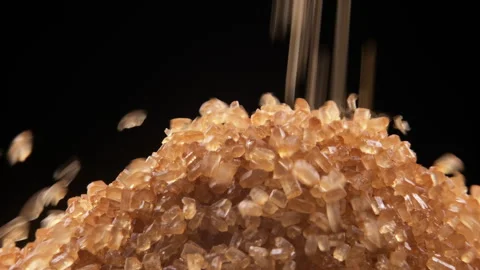 Close up of cane sugar falling onto a mountain of brown sugar. Black background Stock Footage 254104024