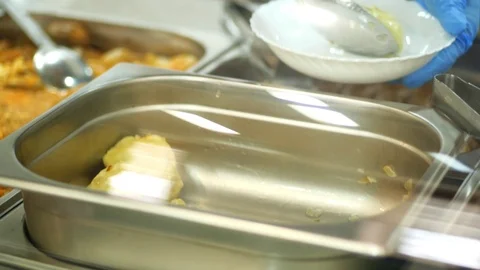 Close-up, canteen worker lays a portion of dumplings on the plate. in modern Stock Footage 103578338