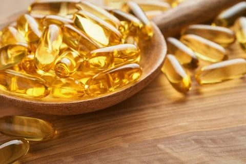 Close up capsules with Vitamin D, E or Omega 3,6,9 fatty acids in bottle on o Stock Photos