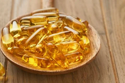 Close up capsules with Vitamin D, E or Omega 3,6,9 fatty acids in bottle on o Stock Photos