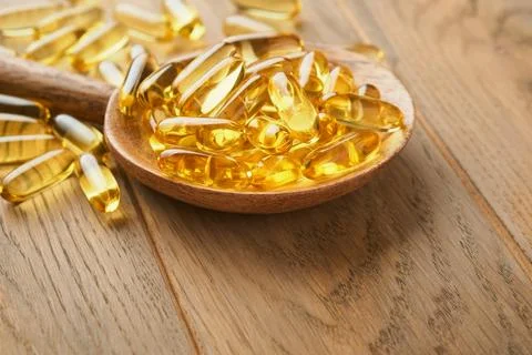 Close up capsules with Vitamin D, E or Omega 3,6,9 fatty acids in bottle on o Stock Photos