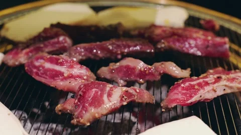 Close-up captures fresh raw beef being grilled at a Korean barbecue restaurant. Vídeo Stock 325079305