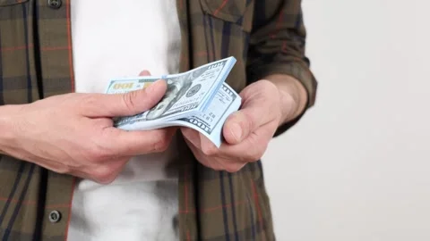 A close-up captures men's hands carefully counting a stack of dollar banknotes Stock Footage 307416919